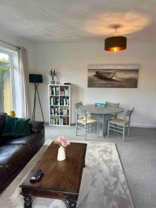 een woonkamer met een bank en een tafel bij Spindrift, Spacious bungalow near beach in Hamworthy