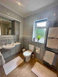 a bathroom with a toilet and a sink and a window at Spindrift, Spacious bungalow near beach in Hamworthy