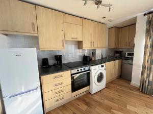 a kitchen with wooden cabinets and a washer and dryer at Victoria suite in London