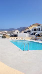 a swimming pool with blue water and white buildings at Beach Apartment la Arena in Puerto de Santiago