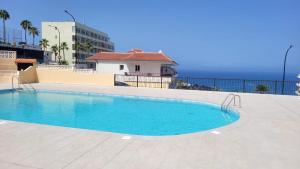 a swimming pool on top of a building with the ocean in the background at Oceanfront Beach Apartment la Arena in Puerto de Santiago