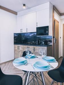 Apartamenty Pod Brzezinami في مورزاسيخله: طاولة بيضاء مع الأطباق وكؤوس النبيذ