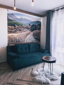 a living room with a green couch and a painting at Apartamenty Pod Brzezinami in Murzasichle