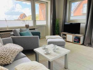 a living room with couches and a table and a tv at Düne 77 Moderne Ferienwohnung in Baltrum