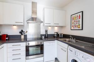 a kitchen with white cabinets and a sink at City-Close 1-Bed Apartment near Tower Hill in London