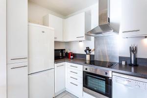 a kitchen with white cabinets and a stove top oven at City-Close 1-Bed Apartment near Tower Hill in London