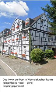 een groot wit en zwart gebouw op een straat bij Hotel zur Post Dabringhausen - contactless self check-in in Wermelskirchen