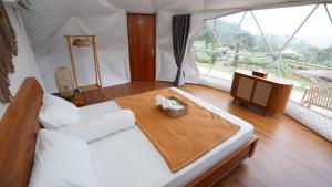 a bedroom with a bed with a table and a window at Tiris Pisan Glamping & Resort Puncak in Cikuray +46 photos