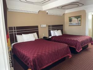 duas camas num quarto de hotel com lençóis vermelhos em Budget Inn and Suites Corpus Christi em Corpus Christi