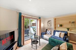 a living room with a blue couch and a tv at Stunning Central London 2 Bed Parking & Garden in London