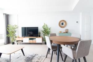 een woonkamer met een tafel en stoelen en een televisie bij Global Properties, Nuevo apartamento con terraza en Gran Canet Residencial in Canet de Berenguer