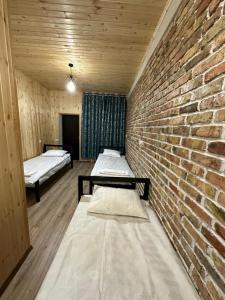 Zimmer mit 2 Betten und Ziegelwand in der Unterkunft Kerben House in Naryn