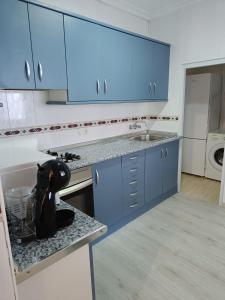 a kitchen with blue cabinets and a counter top at Holiday apartment in Puerto de Sagunto
