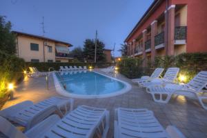 Una piscina con tumbonas y un hotel. en Holidays alle rose, en Peschiera del Garda