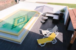 的住宿－Retiro da Atafona Beach Pool House White，游泳池配有椅子和遮阳伞,旁边设有桌子和遮阳伞