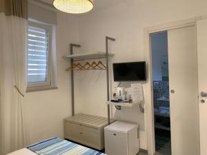 1 dormitorio con 1 cama y TV en la pared en Dimora del Corso - Rooms, en Mattinata