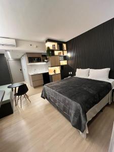 a bedroom with a large bed and a desk and a table at Flat Pleasure in Goiânia