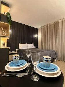戈亞尼亞的住宿－Flat Pleasure，一间设有床和一张带盘子及眼镜的桌子的房间