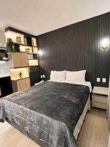 a bedroom with a large bed with a black wall at Flat Pleasure in Goiânia