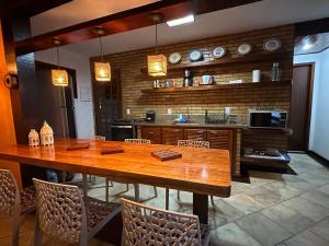 uma cozinha com uma grande mesa de madeira e cadeiras em Aconchegante Casa Buzios em Búzios