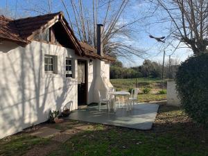 ein kleines weißes Haus mit einem Tisch und Stühlen in der Unterkunft Altos de la Laguna in Chascomús
