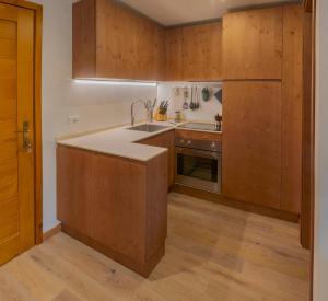 una cucina con armadi in legno e lavandino di Appartamento con terrazza di mq 40 con vista Pale di San Martino a San Martino di Castrozza