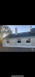 uma casa com três janelas e um telhado em Clonmines lodge em Wexford