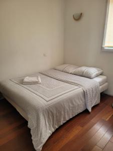 1 cama blanca en un dormitorio con suelo de madera en Cabanès des Aresquiers avec jacuzzi, en Frontignan