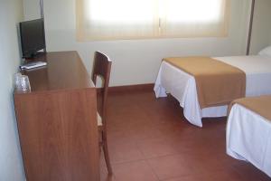 Habitación con 2 camas y un podio con TV. en Hotel Restaurante Los Prados, en Loeches