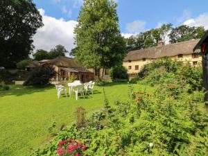 a garden with tables and chairs in front of a building at The Milking Parlour in Beaworthy