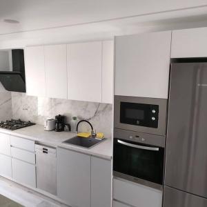 una cocina con armarios blancos y un aparato de acero inoxidable en Apartamento nuevo muy centrico, en Denia