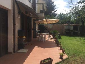 a patio with a table and an umbrella at Appartamento con giardino a Selcetta vicino Campus Biomedico in Selcetta