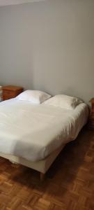 łóżko z białą pościelą i poduszkami na drewnianej podłodze w obiekcie La maison Do w mieście Lunas
