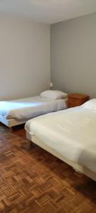 2 łóżka w pokoju z drewnianą podłogą w obiekcie La maison Do w mieście Lunas