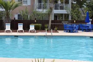 uma piscina com cadeiras, mesas azuis e guarda-sóis em Brunswick Plantation Studio Home 407L with Onsite Golf Course and Pools studio em Calabash