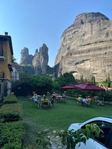a group of people sitting at tables in front of a mountain at Archontiko Mesohori Meteora in Kalabaka