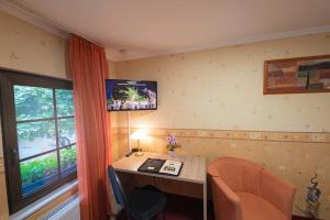 Habitación con escritorio y TV en la pared. en Hotel Am Rathaus en Menden