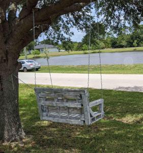 a wooden swing hanging from a tree at A Treasure Coast Gem. in Port Saint Lucie