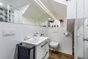 a white bathroom with a sink and a toilet at Cozy Carmelite apartment in Vilnius