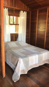 a bed in a wooden room with a window at Chalé Hibisco Amarelo in Juquitiba