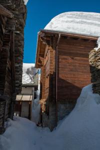 una cabaña de madera en la nieve con nieve en el techo en Zwargji, en Formazza