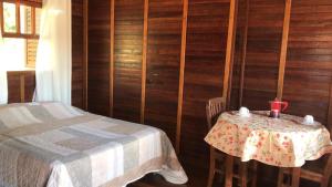 a room with a table and a bed and wooden walls at Chalé Hibisco Amarelo in Juquitiba
