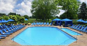 una piscina con sillas y sombrillas azules en Hilton Chicago Oak Brook Hills Resort & Conference Center, en Oak Brook