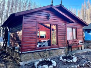 a log cabin with a large window in a yard at La Comarca Azul in El Calafate