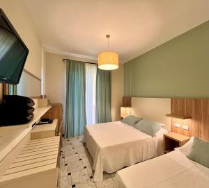 a hotel room with two beds and a flat screen tv at Albergo Degli Amici in Monterosso al Mare