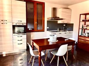 cocina con mesa de madera y sillas blancas en Casa Cavour, en Montecatini Terme