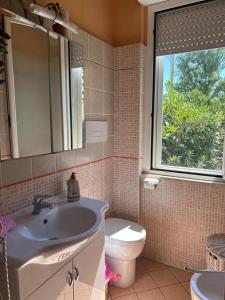 a bathroom with a sink and a toilet and a window at L'angolo della felicità in Marina di Montenero