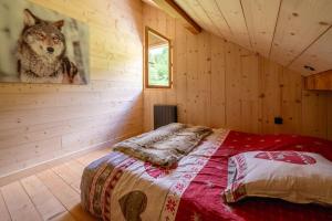 ein Schlafzimmer mit einem Bett in einem Blockhaus in der Unterkunft Chalet le Bois de Cerf in Le Bouchet-Mont Charvin