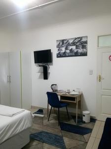 1 dormitorio con escritorio, 1 cama y TV en Pinto City Motel en Kempton Park