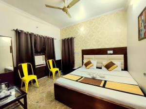 a bedroom with a bed and two yellow chairs at Goroomgo Krishna Residency Bareilly in Bareilly